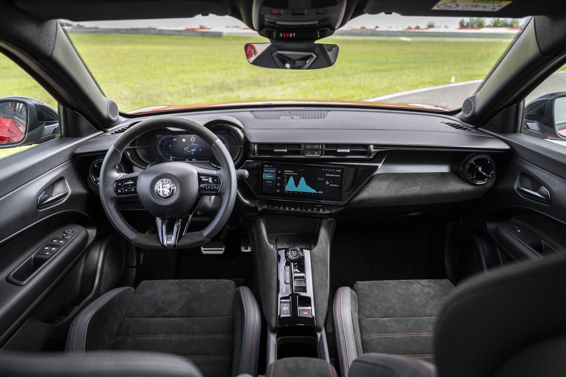 Cabin of the Alfa Romeo Junior seen from behind the front seats, showing the 10.1-inch central touchscreen and the flat-bottom steering wheel. Photo: Stellantis Media, media.stellantis.com/de-de/alfa-romeo/media-library/press-images.
