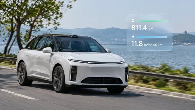 A white Li Auto i6 SUV driving on a road near Lake Tai, with the livestream result graphic showing 811.4 km and 11.8 kWh/100 km next to the car. AI-generated illustration.
