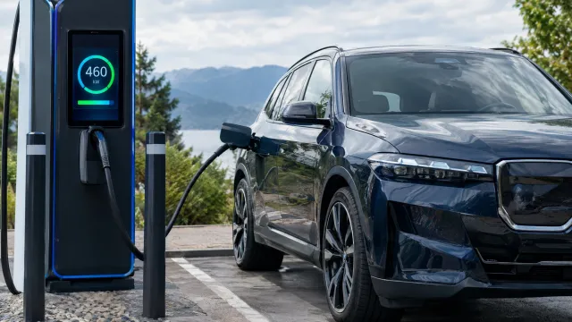 A BMW iX5 standing at a public fast-charging stall with the charger display showing 460 kW during the first public demo session. AI-generated illustration.